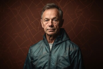 Portrait of a senior man in a jacket on a brown background