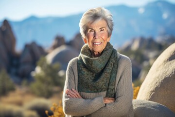 Portrait of smiling senior woman standing with arms crossed on nature background