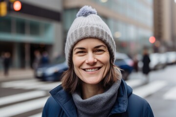 Fototapeta premium Portrait of a smiling woman in a hat and blue jacket in the city
