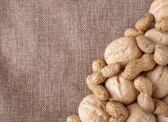 Mixed nuts on a white wooden fabric texture background.