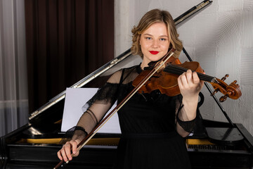 Young elegant blonde girl posing with a violin. Portrait of a female violinist playing, performing...