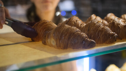 the girl seller puts croissants for sale on the bakery window.