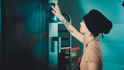 the baker girl touches the oven control panel with her finger.