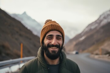 Handsome young man with beard and mustache smiling in the mountains