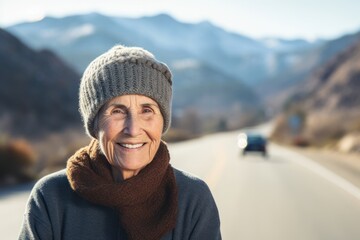 Fototapeta na wymiar Medium shot portrait photography of a pleased woman in her 70s wearing a warm beanie or knit hat against a mountain pass or winding road background. Generative AI