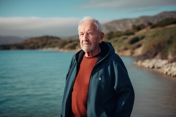 Fototapeta premium Portrait of a senior man standing by the sea on a sunny day
