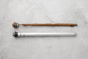 New and old magnesium anode rod on a gray concrete background. The concept of maintenance and repair of electric water heaters.