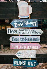 A signpost in front of a beach bar with many signs saying something about beer. Lots of quotes...