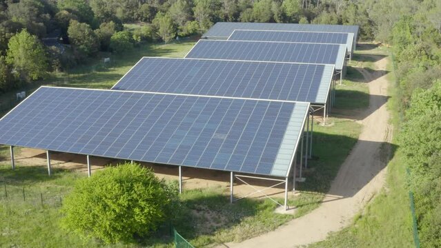 Aerial shot that rises above a solar panel farm in the forest in the countryside