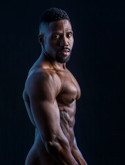 Fototapeta na wymiar Handsome black male bodybuilder posing in studio shot, profile