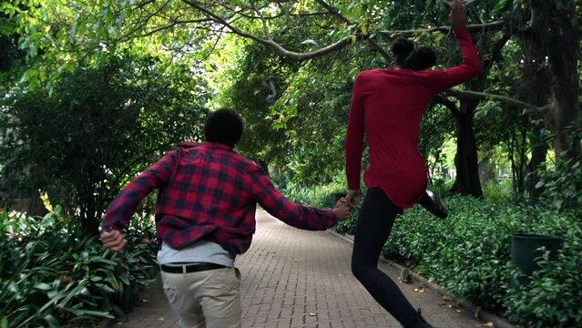 Running, holding hands and love with black couple in park for romance, date and freedom. Peace, nature and support with man and woman playing together in garden for affectionate, bonding or summer
