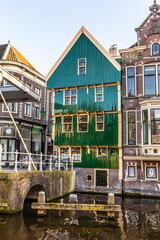 Fototapeta na wymiar An old house with a wooden facade painted green. Alkmaar. Netherlands