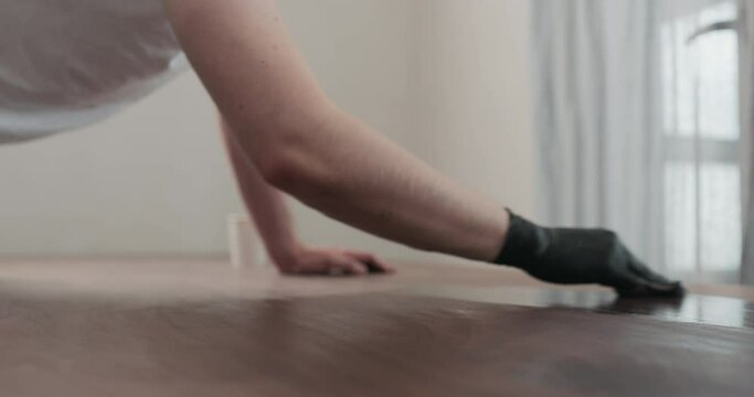 Slow motion of man hand applying oil finish to toned walnut table with cloth