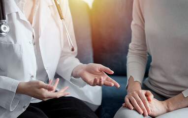 Unknown doctor and patient discussing current health examination while sitting at sofa, closeup. Medicine concept