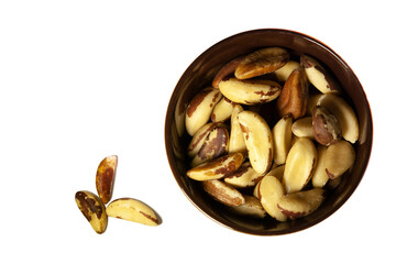 Brazil nuts in a dark ceramic bowl. Top view. Isolated.