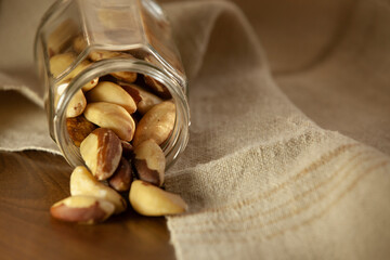 Brazil nuts pouring out of the jar onto the table. Selective focus.