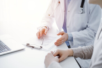 Doctor and patient discussing current health questions while sitting at the table in clinic office, only hands closeup. Medicine concept