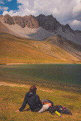 Fototapeta premium A male hiker sitting next to a mountain lake, Lac de Soulier (Hautes-Alpes)