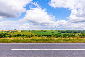 Fototapeta premium Empty asphalt rural road with agriculture field, grassland and blue sky with white clouds. Road background.