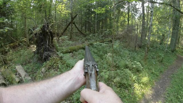 A man pointing a shot gun on the woods looking for target on a hunt