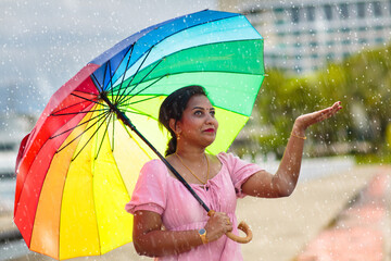 Young woman walking in rain with umbrella