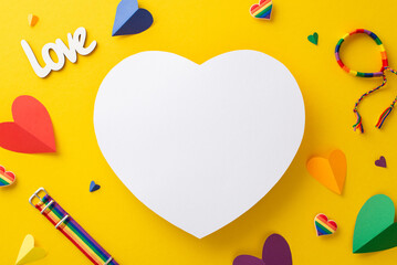 Top view flat lay of LGBT Pride accessories, including pins, bracelet and wristbands, on a vibrant yellow background with an empty heart for text