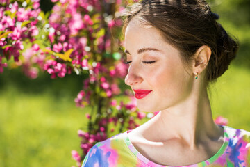 Young beautiful woman posing in lilac bushes