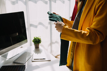 Fashion designer l young asian woman working using laptop, tablet and smiling while standing in workshop Responding on business