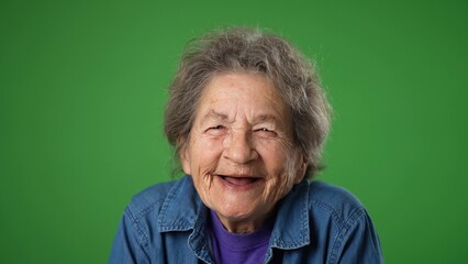 Closeup portrait of smiling happy toothless elderly senior old woman with wrinkled skin and grey hair isolated on green screen background in studio. Emotions concept