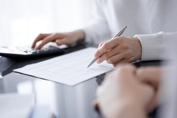 Woman accountant using a calculator and laptop computer while counting taxes for a client. Business audit concepts