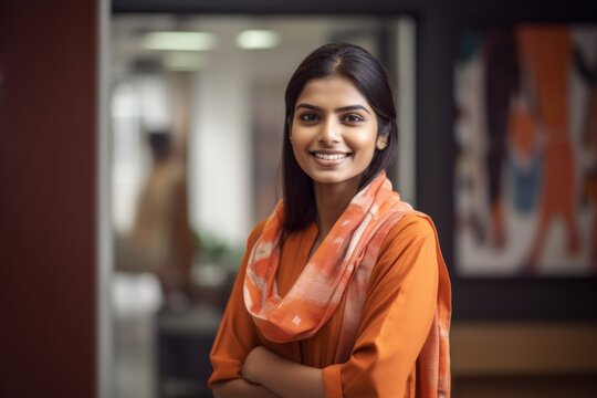 Young smart indian businesswoman, smiling face, standing in blur background of creative colorful office interior design. Generative AI AIG20.