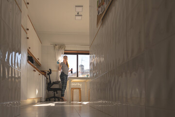 Adult housewife woman standing in the kitchen with a rag to wipe the windows