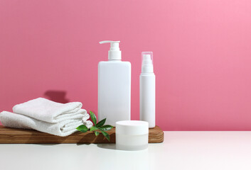 mockup of cosmetic bundle for skin hair care. White plastic bottles and tubes with black caps in...