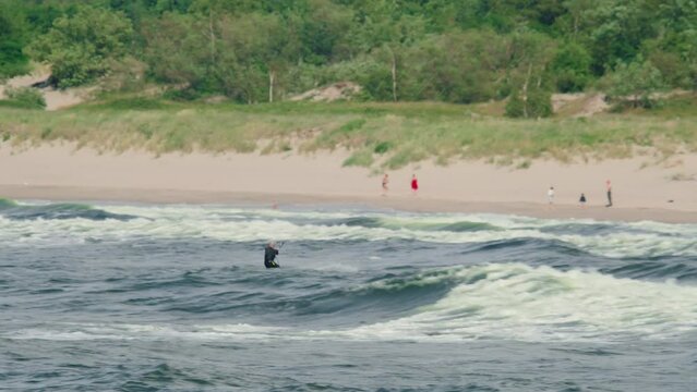 Exhilarating scene of a man kite surfing on the waves near the shore. Man skillfully maneuvers the kite and rides the waves with confidence and agility with the picturesque background of sparkling