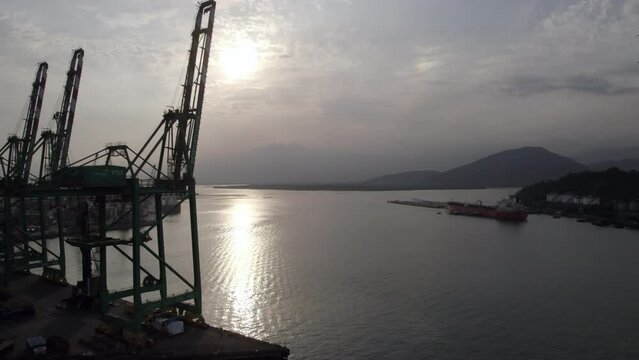 Containership cranes at empty shipping port - aerial view showing setting sun behind clouds
