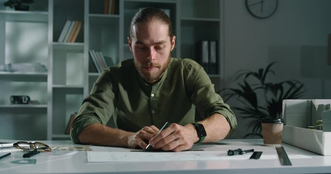 Portrait of a caucasian handsome architect drawing lines on paper.