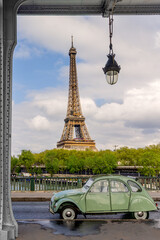 Paris, Eiffel Tower and an old classic  green French car.  Viewed from on the bridge at Pont Bir de...