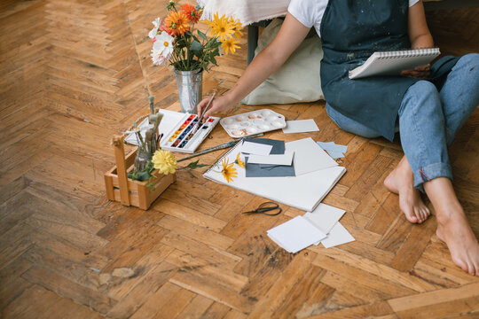 Overhead view of a woman sitting on the floor painting with watercolour paints