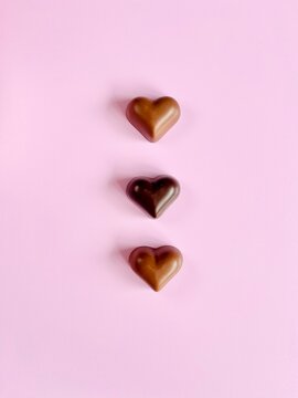 Overhead view of milk and dark chocolate hearts on a pink background