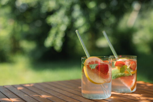 Close-up of two summer drinks with fresh fruit on a table in dappled light