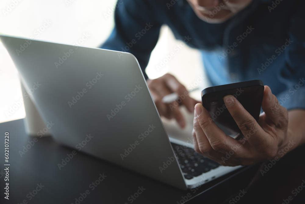 Poster close up of business man working on laptop computer and using mobile phone with digital tablet on of