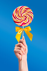 Woman holding colorful lollipop on blue background