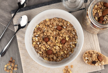 Crispy granola with nuts in bowl on light table background. Healthy cereal breakfast. Top view.