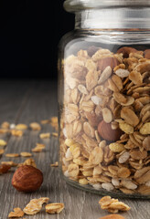 Homemade granola in jar on kitchen table, healthy breakfast of oatmeal muesli, nuts, seeds and dried fruit.