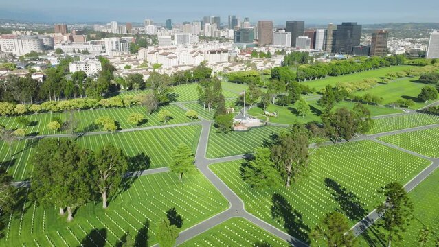 Aerial view if Westwood Los Angeles suburban town with National Cemetery park, California USA. Drone above green field with straight rows of white grave plates on summer day. Armed forces cemetery 4K