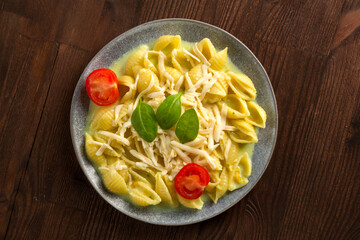 Pasta in cream sauce with cheese garnished with spinach and cherry tomatoes with a fork on a wooden table.