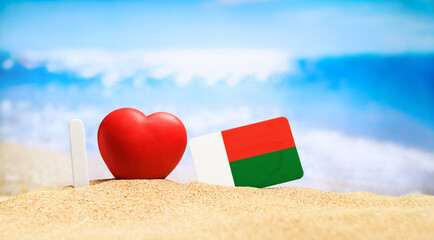 Flag of Madagascar on the beach with a red heart. vacation and travel concept.