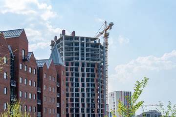Industrial construction cranes work above new modern building. Engineering multistory design from concrete block and overlap. Development high-rise apartment with place for windows and balconys.