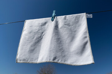 Clothes peg on a towel and washing line against a blue sky