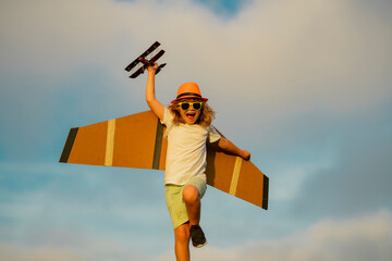 Child playing. Dream of flying. Little children with toy airplane in a field at sunset. Success and...